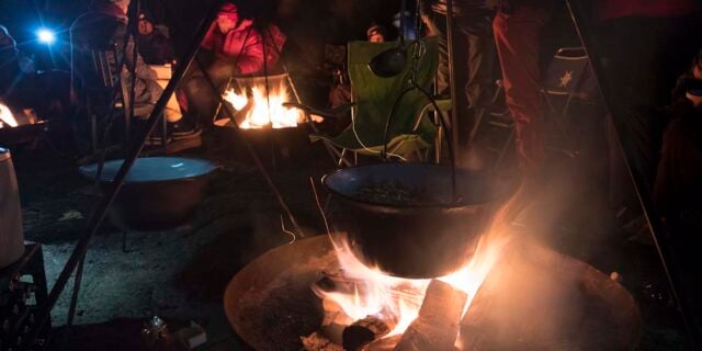 cooking over a campfire with a tripod